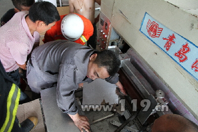 图为工人的手被卡在印刷机内